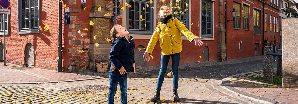 Kinder tanzen in Blätterregen