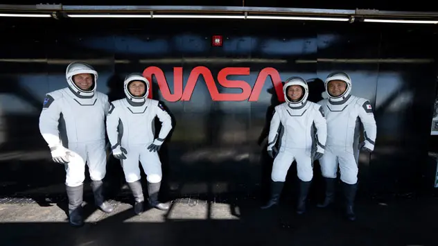 NASA’s SpaceX Crew-5 astronauts are photographed in front of the agency’s iconic worm logo at