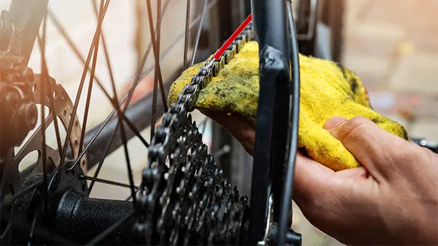 Eine Fahrradkette wird mit einem Lappen gereinigt. 