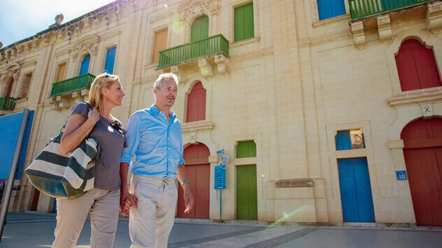 Mann und Frau laufen vorbei an alten Gebäuden auf Malta