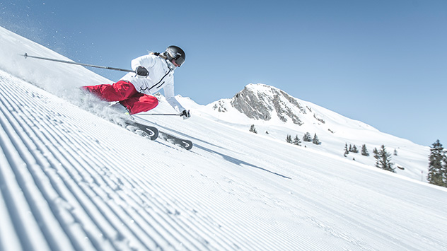 Ein Skifahrer auf einer Piste bei Sonnenschein