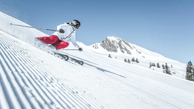 Ein Skifahrer auf einer Piste bei Sonnenschein
