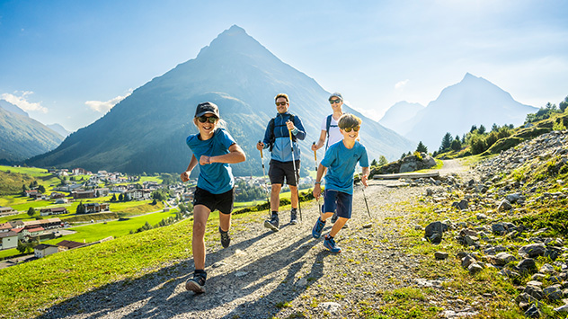 Eine Familie ist unterwegs auf einem Wanderweg mit Bergpanorama