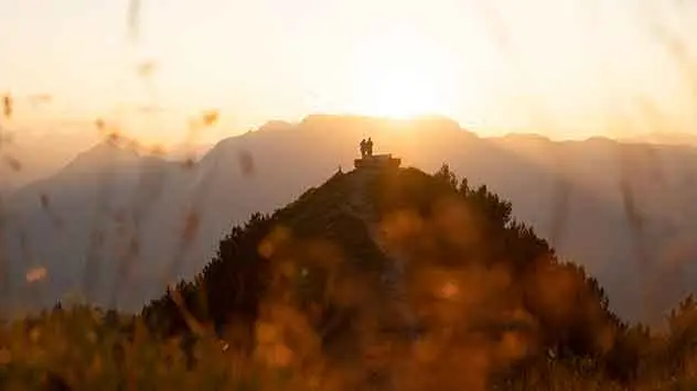 Eine Frau dem Gipfelkreuz der Gratlspitze