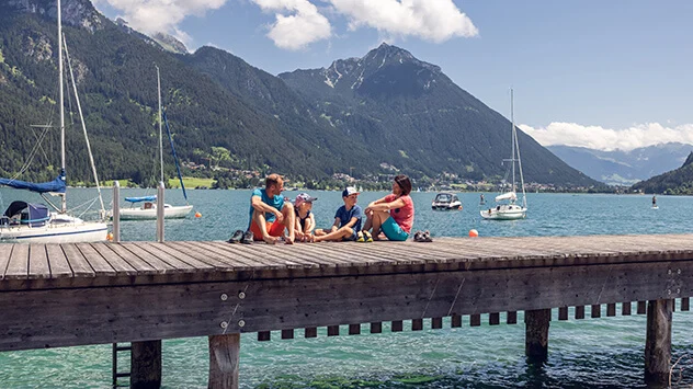 Familie sitzt auf einem Steg am Achensee