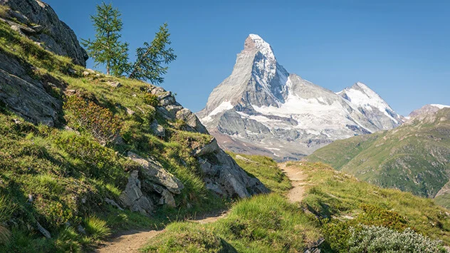 Blick von einem schmalen Wanderpfad auf das verschneite Matterhorn am Horizont