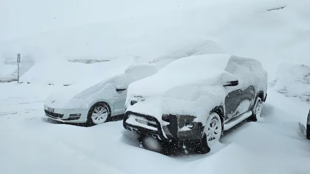 Heavy snow covers cars in the Alps.