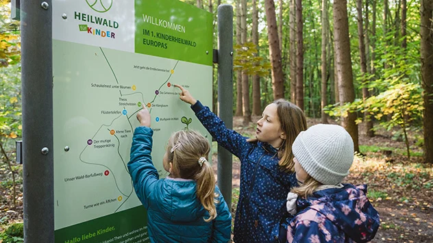 Kinder vor einem Wegplan im Kinderheilwald