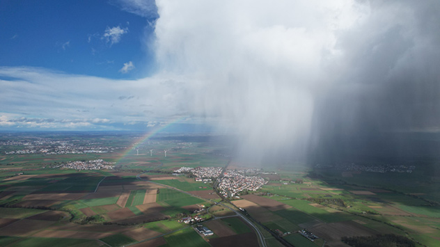 Eine Schauerwolke "spuckt" einen Regenbogen aus.
