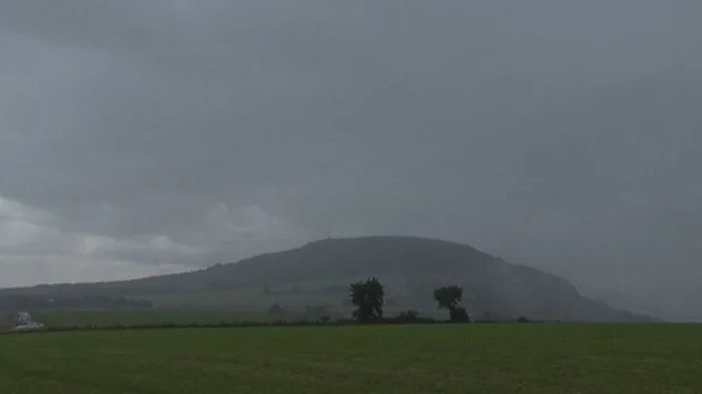 Tief hängende Nimbostratus-Wolken bringen Regen über ländliche und grüne Sommerlandschaft.