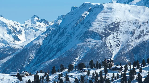 Blick auf verschneiten Berghang und Dorf im Tal