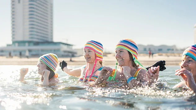 Frauen mit bunten Häkelmützen baden in der eisigen Ostsee