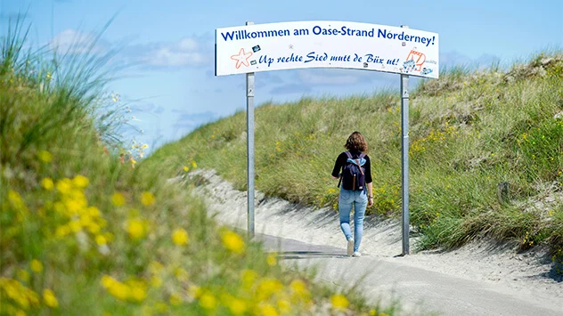 Frau schlendert zum Aufgang des Oase-Strand Norderney