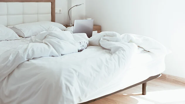 Aufgeschlagenes Bett mit weißer Bettwäsche