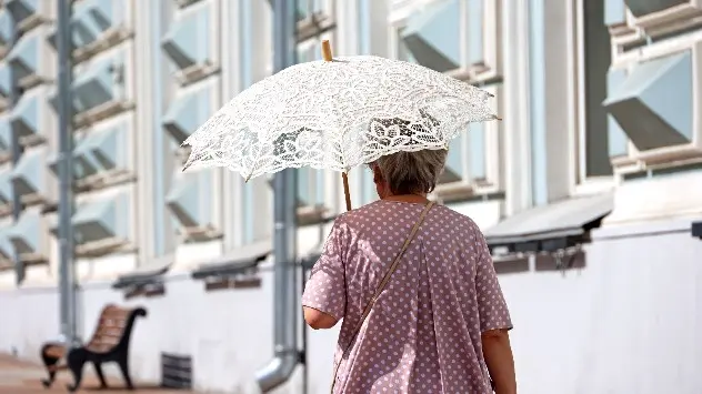 Ältere Frau mit Sonnenschirm im Sommer