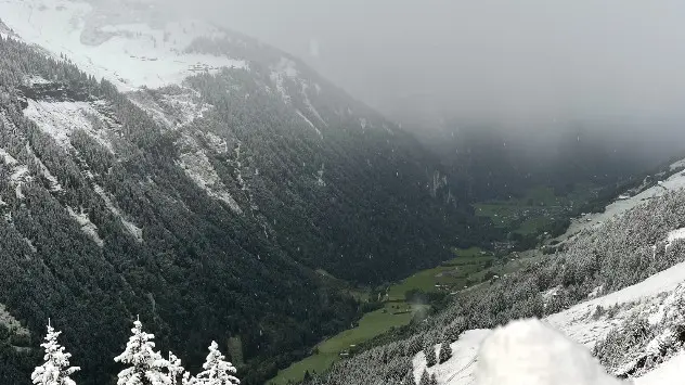 Schneeflocken fallen vom Himmel - im Tal ist es noch grün