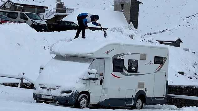 sne alperne person skovler sne af autocamper