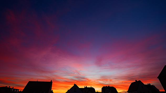 Violett leuchtende Wolken über Kirchhain - am Horizont noch orangenen Streifen durch Abendrot.