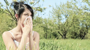 Frau reagiert auf Gräserpollen mit Niesen - Taschentuch