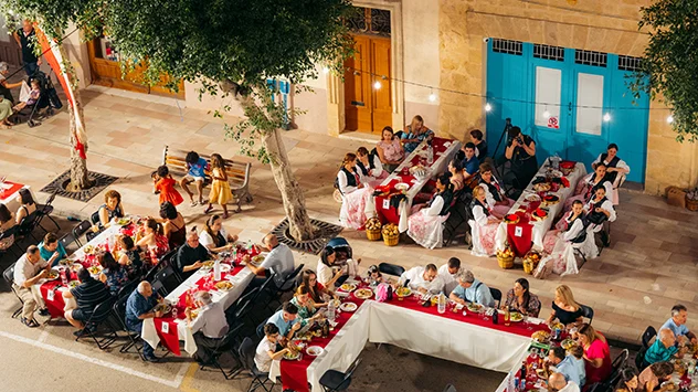 das Fest von Nadur auf Gozo: Viele Menschen essen an großen Tischen gemeinsam auf der Straße. 