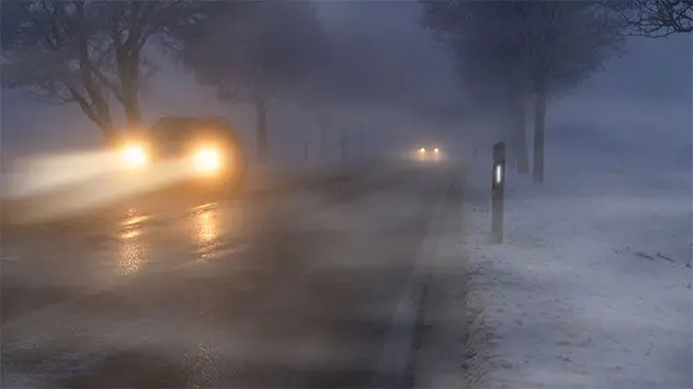 Autos im Nebel auf einer dunklen Landstraße