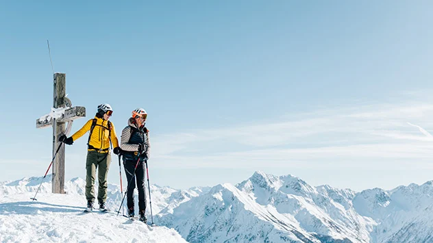 Zwei Wanderer auf einem Berg mit Gipfelkreuz