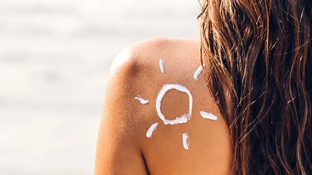 Rücken einer Frau mit einer Sonne aus Sonnenmilch