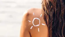 Rücken einer Frau mit einer Sonne aus Sonnenmilch