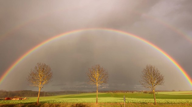 Über den Wiesen bei Pohlheim in Hessen spannt sich ein Doppelregenbogen auf. 