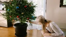Eine Frau dekoriert einen Weihnachtsbaum, der im Topf steht. 