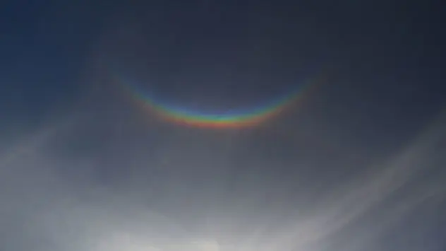 Regenbogenfarbiger Lichtring an einem wolkigen Himmel