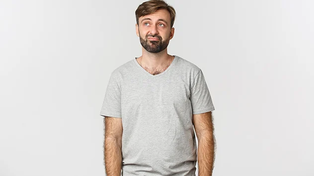 Mann um Mitte 30 in weißem T-Shirt vor Raum mit weiß bemalter Backtsteinwand
