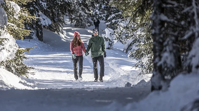 Ein Paar unternimmt eine Winterwanderung bei Sonnenschein. 