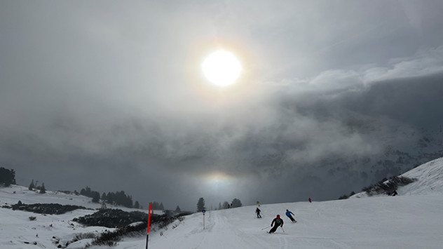 Skiërs kwispelen de zon tegemoet in de Radstädter Tauern. In de richting van het dal is duidelijk een zogenaamde onderzon te zien.