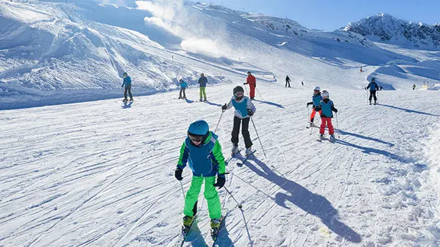 Kinder fahren Abfahrt auf Skiern im Zillertal herunter