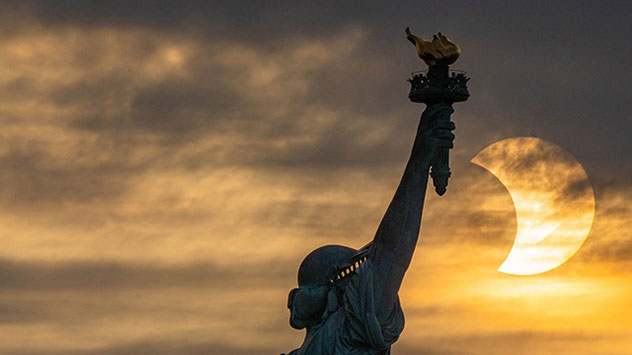 Die Freiheitsstatue auf Liberty Island bei New York vor der verfinsterten Morgensonne. 