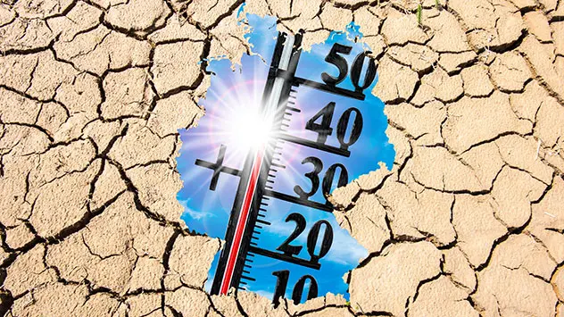 Symbolbild: Deutschland als Umriss mit Thermometer über ausgetrocknetem Boden mit Rissen