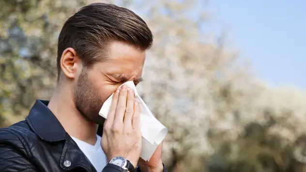 Man sneezes into tissue