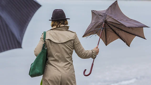Frau mit Schirm, der durch starken Wind kaputtgegangen ist