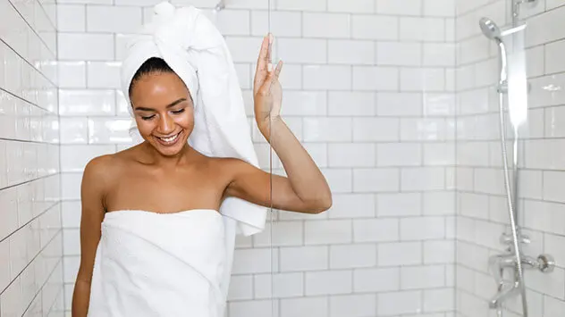 Frau steigt frisch geduscht aus der Dusche