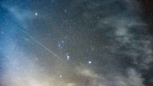 Un meteor văzut pe cerul nopții în dreptul constelației Orion.