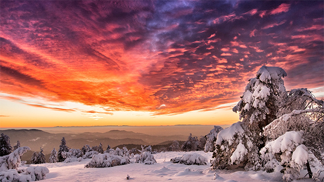 Das Bild zeigt einen Himmel in brennenden Farben über einer Schneelandschaft 