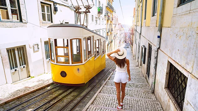 Urlauberin steht neben gelber Straßenbahn in Lissabon