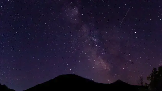 Un meteor din Perseide este văzut pe cerul de seară, sub Calea Lactee.