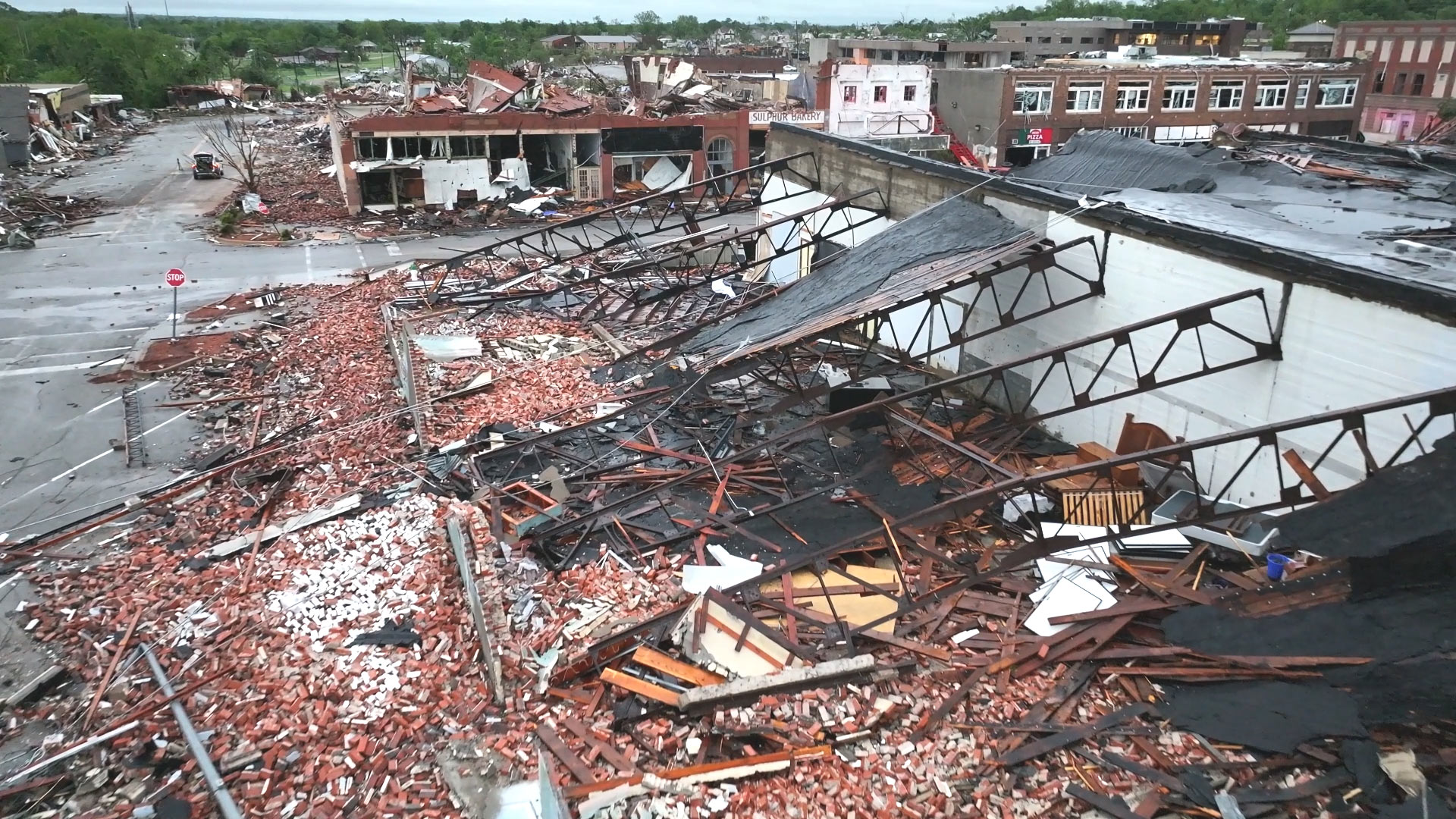 Partial collapse of a commercial building's roof and walls following a tornado strike.