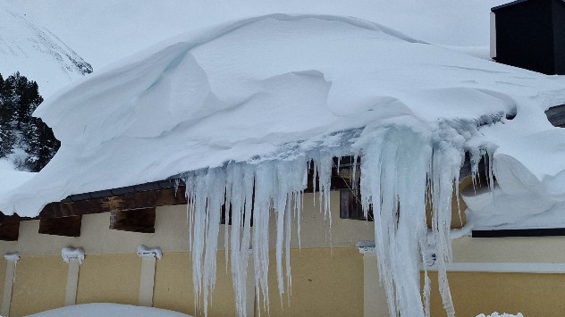 Auf den Hausdächern türmen sich meterhohe Schneewechten und Eiszapfen hängen herunter.