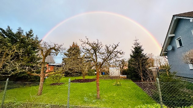 Über dem Garten spannt sich ein Regenbogen auf. 
