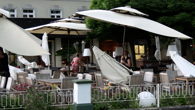 In Reifnitz am Wörthersee versuchen Restaurantbesitzer ihre Sonnenschirme vor dem Sturm zu retten.