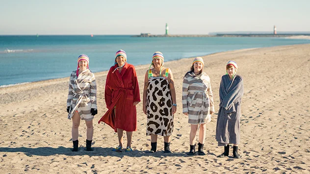 Eisbaden in der Ostsee - Bild: TMV/Gross Fünf Frauen am Strand mit Bademänteln bekleidet.