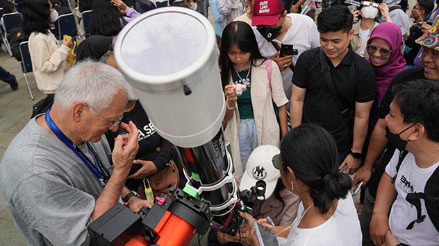 Andere benutzen ein Teleskop, um die Sonnenfinsternis zu beobachten. Die Linse ist mit einem Schutzfilter versehen.